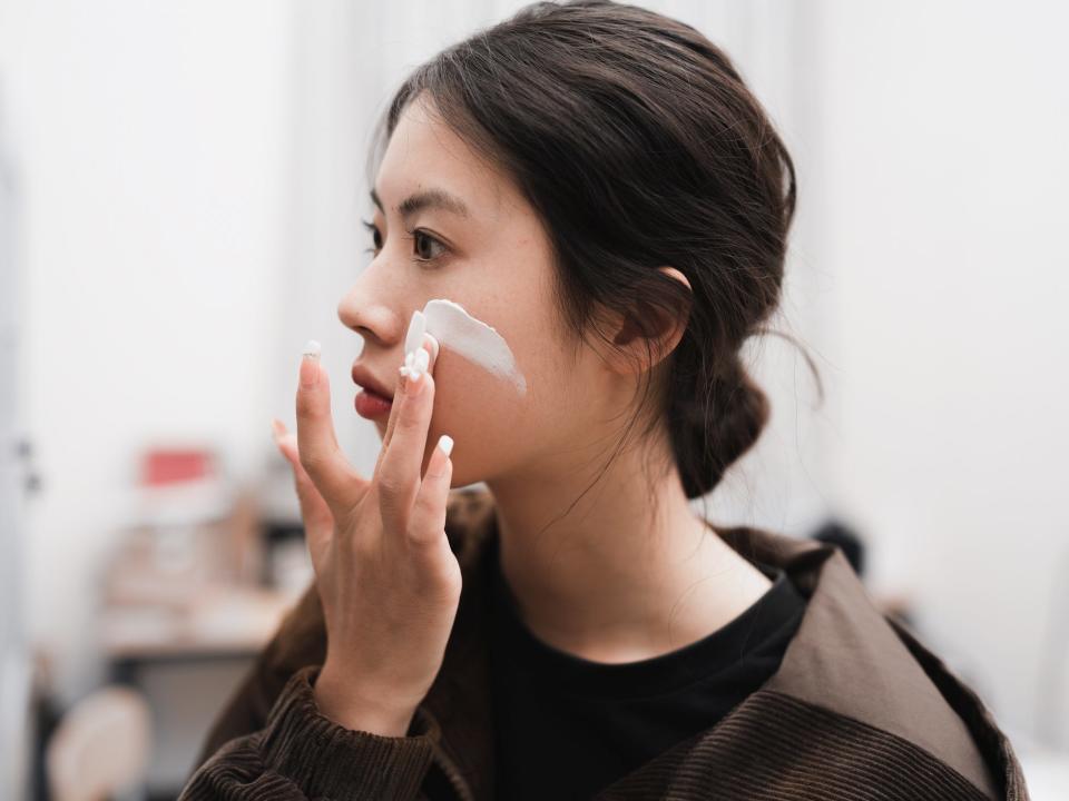 A woman applying moisturizer