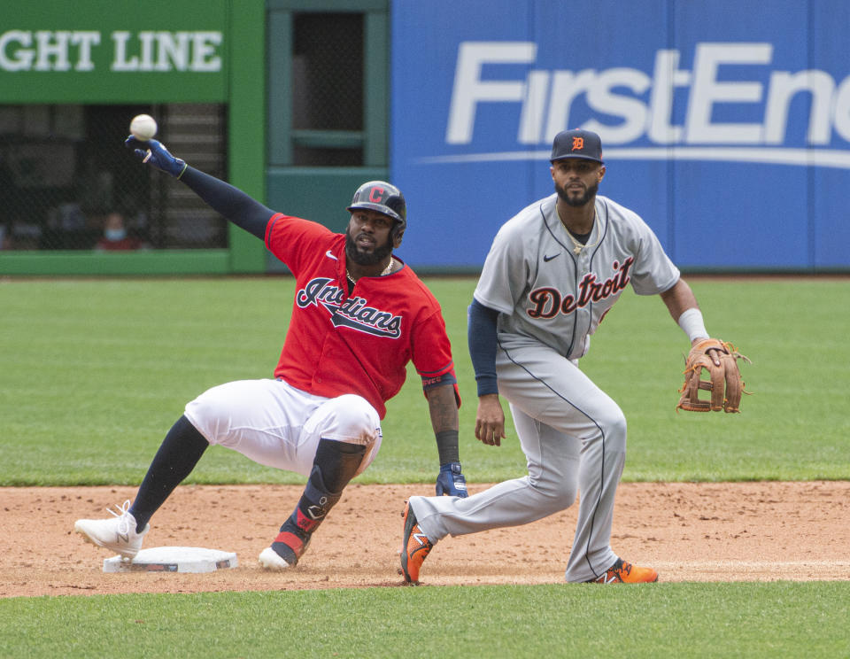 Cleveland Indians' Franmil Reyes is safe at second as the ball gets away from Detroit Tigers' Willi Castro during the sixth inning of a baseball game in Cleveland, Sunday, April 11, 2021. (AP Photo/Phil Long)