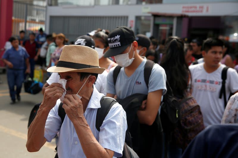 A man wipes his nose while waiting to board a bus at a bus station after Peru's government deployed military personnel to block major roads, as the country rolled out a 15-day state of emergency to slow the spread of coronavirus disease (COVID-19), in Lima