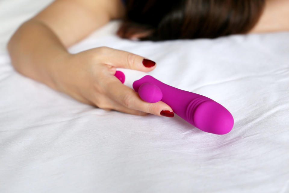 Woman on a bed with purple silicone vibrator 