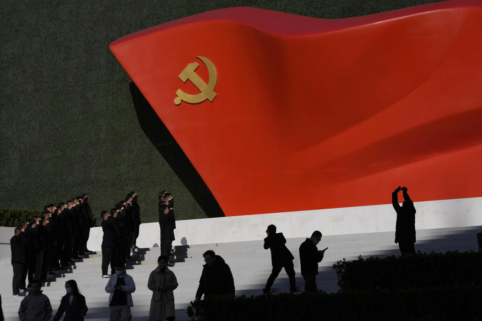 Chinese Communist Party members pose for photos with a sculpture of the party flag outside the Museum of the Communist Party of China in Beijing, China, Friday, Nov. 12, 2021. China says it is a nation "ruled by law," but the Communist Party ultimately holds sway and there are large gray areas of enforcement. Control over the press and social media allows authorities to keep word of disappearances quiet and to stonewall critics, although such news often gradually surfaces through underground and foreign sources. (AP Photo/Ng Han Guan)