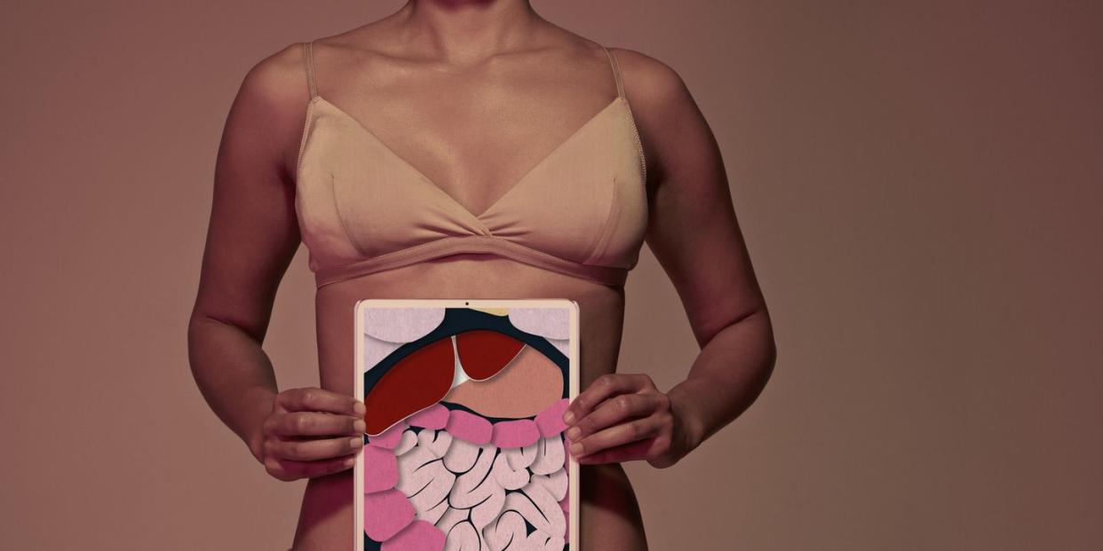 young woman holding tablet in front of stomach to show intestines