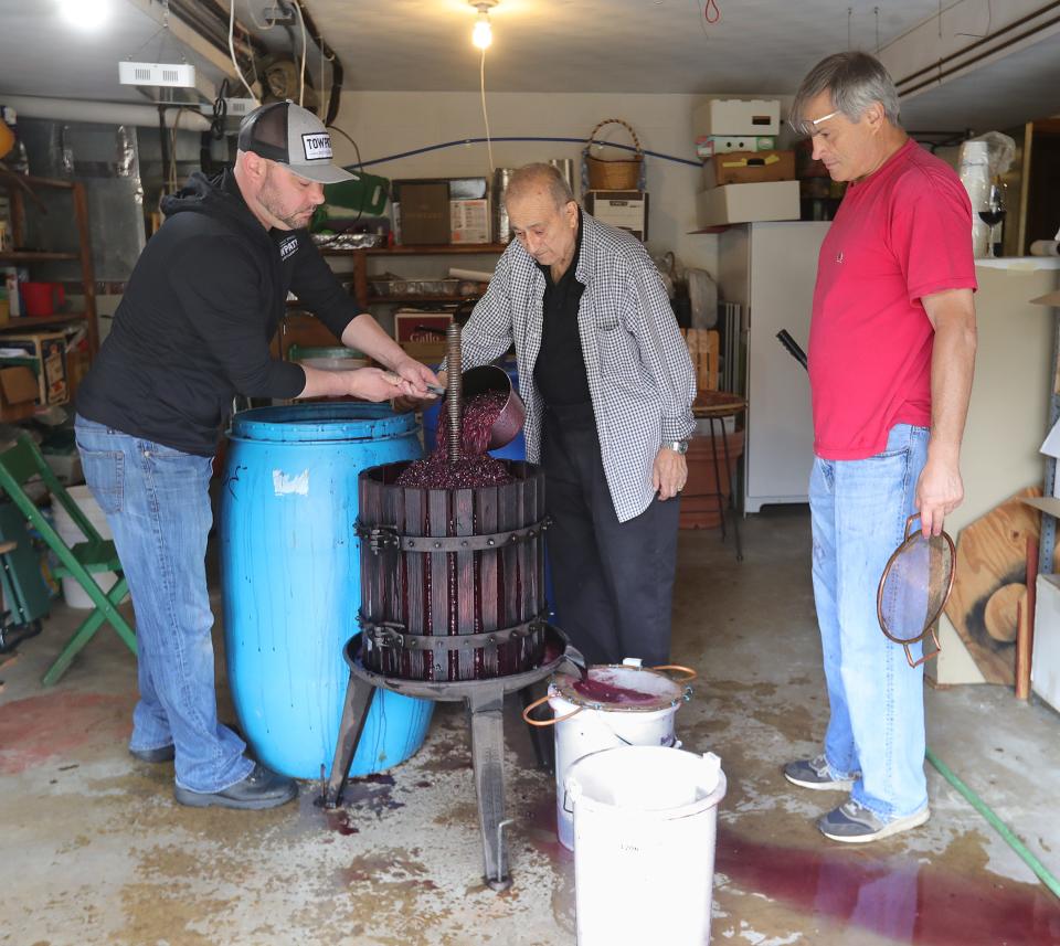 Anthony Piscazzi, left, feeds the wine press May 7 next to his grandfather Joe Piscazzi and uncle Rocco "Rocky" Piscazzi in Cuyahoga Falls.