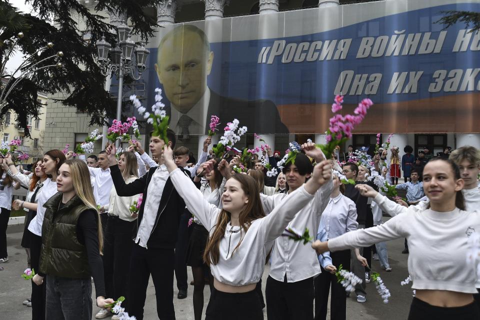 Youth take part in an action to mark the ninth anniversary of the Crimea annexation from Ukraine with the banner reads: "Russia doesn't start wars, it ends them" accompanied with an image of Russian President Vladimir Putin in Yalta, Crimea, Friday, March 17, 2023. (AP Photo)