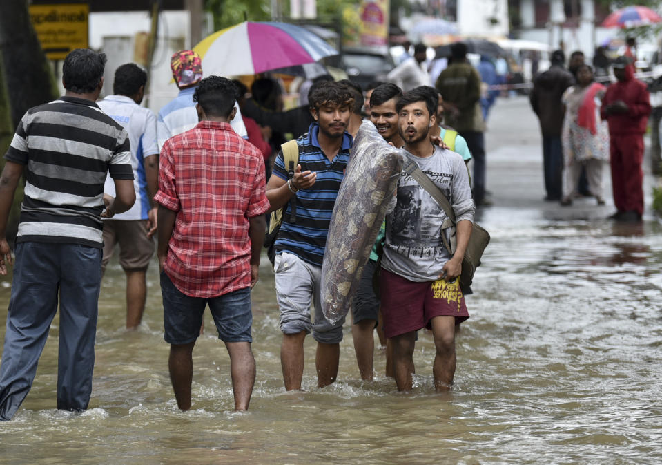 Numerosas personas cruzan zonas inundadas debido a las fuertes lluvias monzónicas en Thiruvananthapuram, estado de Kerala, en India, el miércoles 15 de agosto de 2018. El transporte aéreo y ferroviario quedó suspendido debido a los aguaceros y las inundaciones en Kerala. La cifra de muertos asciende a 67 en el estado, según las autoridades. (AP Foto)