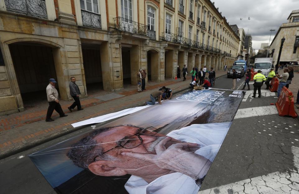 Un grupo de trabajadores se prepara para colgar un letrero con una fotografía del fallecido Gabriel García Márquez en la alcaldía de Bogotá, Colombia, el martes 22 de abril de 2014. García Márquez, quien murió en la Ciudad de México el 17 de abril, es considerado uno de los más grandes escritores de la lengua española de todos los tiempos. (Foto AP/Fernando Vergara)