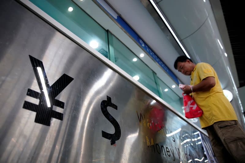 FILE PHOTO: Signs of Chinese yuan and U.S. dollar are seen at a currency exchange store in Shanghai