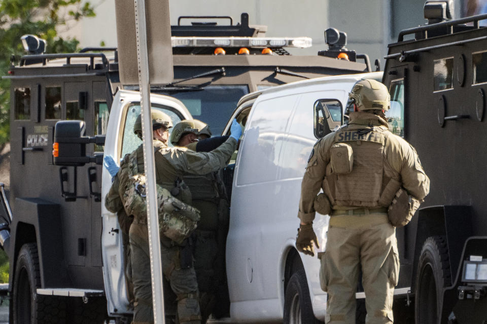 Members of a SWAT team enter a van and look through its contents in Torrance Calif., Sunday, Jan. 22, 2023. An hours-long manhunt led police to surround and enter the van. Authorities say the suspect in a California dance club shooting that left multiple people dead, shot and killed himself. (AP Photo/Damian Dovarganes)