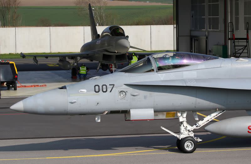 FILE PHOTO: A Swiss Air Force F/A-18C Hornet passes in front of a Eurofighter Typhoon jet during tests in Payerne