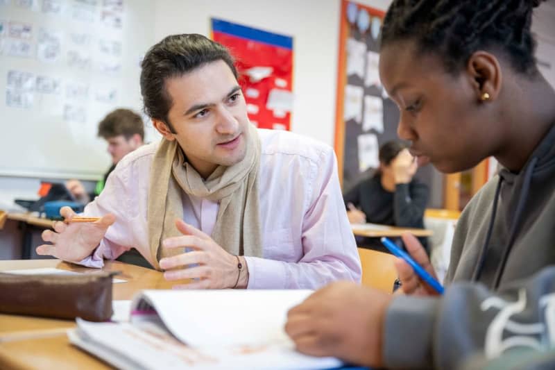 Sargis Poghosyan (left), a participant in the Bremen ‘Study Friends’ project, helps pupils from the Neue Oberschule Gröpelingen in class. Sina Schuldt/dpa