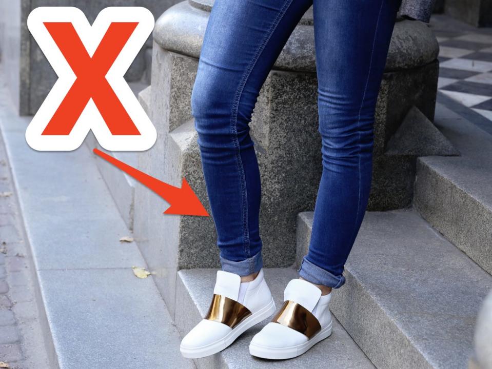 red x and arrow over person walking down steps wearing skinny jeans and white and gold sneakers