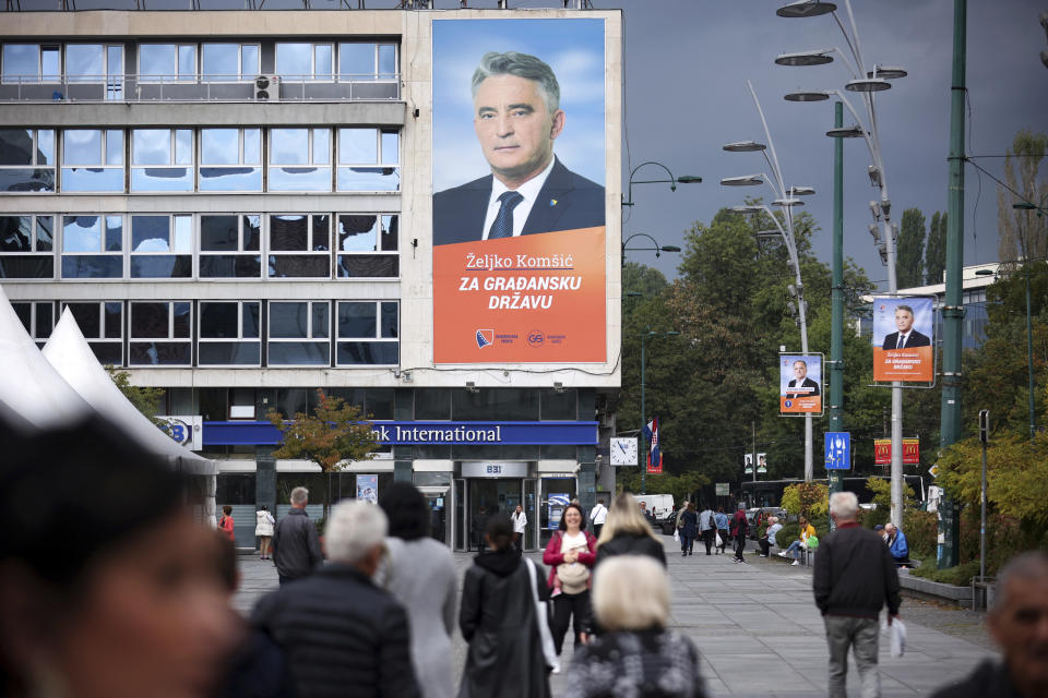 People pass by an election poster of Zeljko Komsic who is running for the Bosnian Presidency on the upcoming elections in Sarajevo, Bosnia, Tuesday, Sept. 27, 2022. Bosnia's upcoming general election could be about the fight against corruption and helping its ailing economy. But at the time when Russia has a strong incentive to reignite conflict in the small Balkan nation, the Oct 2. vote appears set to be an easy test for long-entrenched nationalists who have enriched cronies and ignored the needs of the people. (AP Photo/Armin Durgut)