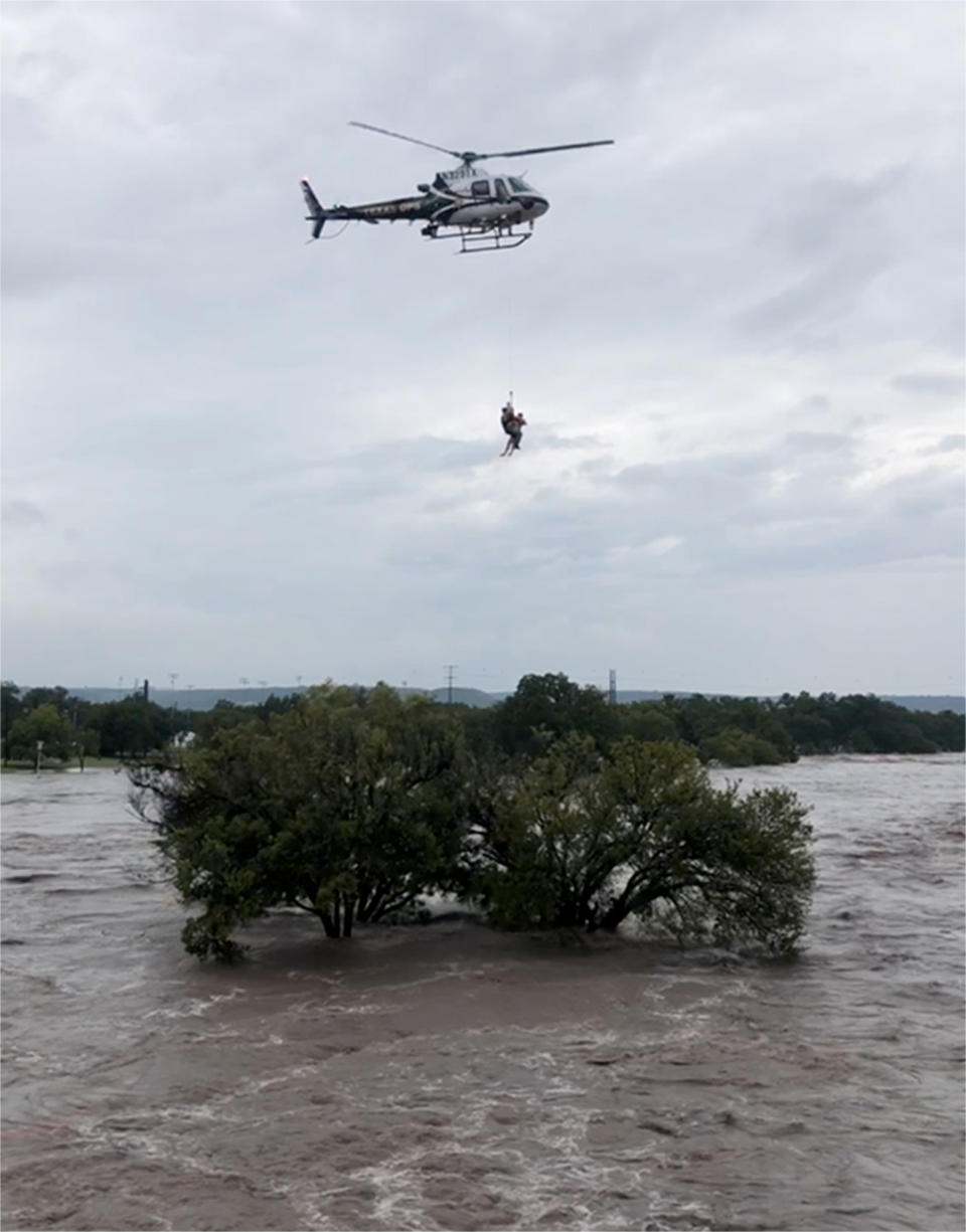 This photo from video provided by the Texas Parks and Wildlife Department shows a helicopter crew from the Texas Department of Public Safety performing a rescue from the South Llano River near Junction, Texas, on Monday, Oct. 8, 2018. Rescue crews in boats and helicopters are searching for several people missing since heavy rain washed away a recreational vehicle park in the small West Texas city. (Texas Parks and Wildlife Department via AP)