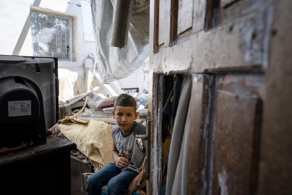 Abu Amsha, 6, sits for a portrait in his bedroom that was damaged when an airstrike destroyed the neighboring building prior to a cease-fire that halted an 11-day war between Gaza's Hamas rulers and Israel, Wednesday, May 26, 2021, in Beit Hanoun, Gaza Strip. (AP Photo/John Minchillo)