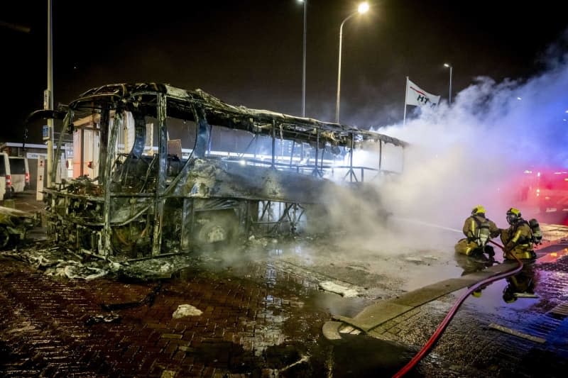 Firefighters extinguish a burning bus at the Opera House on Fruitweg following a confrontation between two groups of Eritreans after riots broke out following a meeting at the conference center. Robin Utrecht/ANP/dpa