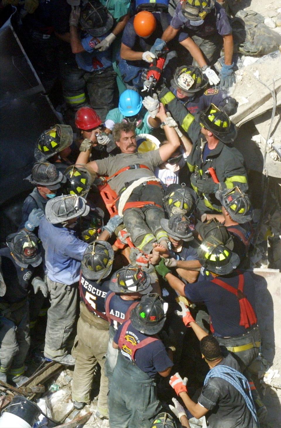 A rescue worker is pulled from the rubble (Getty)