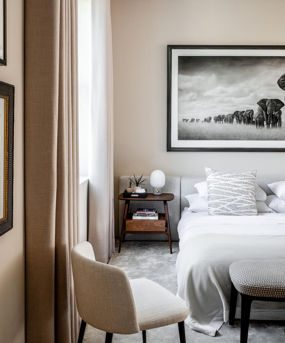 neutral bedroom with soft gray headboard, elephant photograph and mid century style bedside table