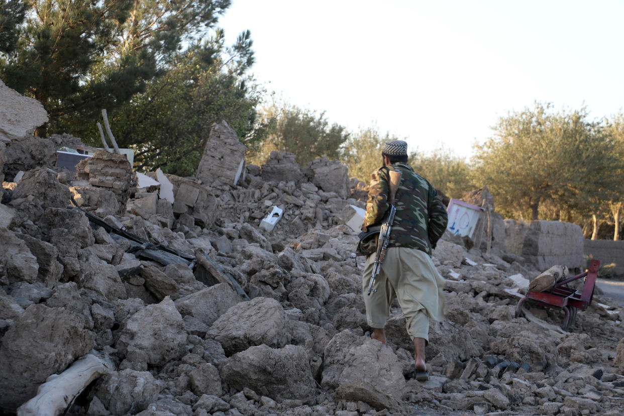 An Afghan man walks by a destroyed home.