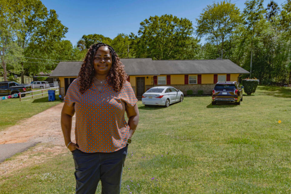 A woman standing outside of her home