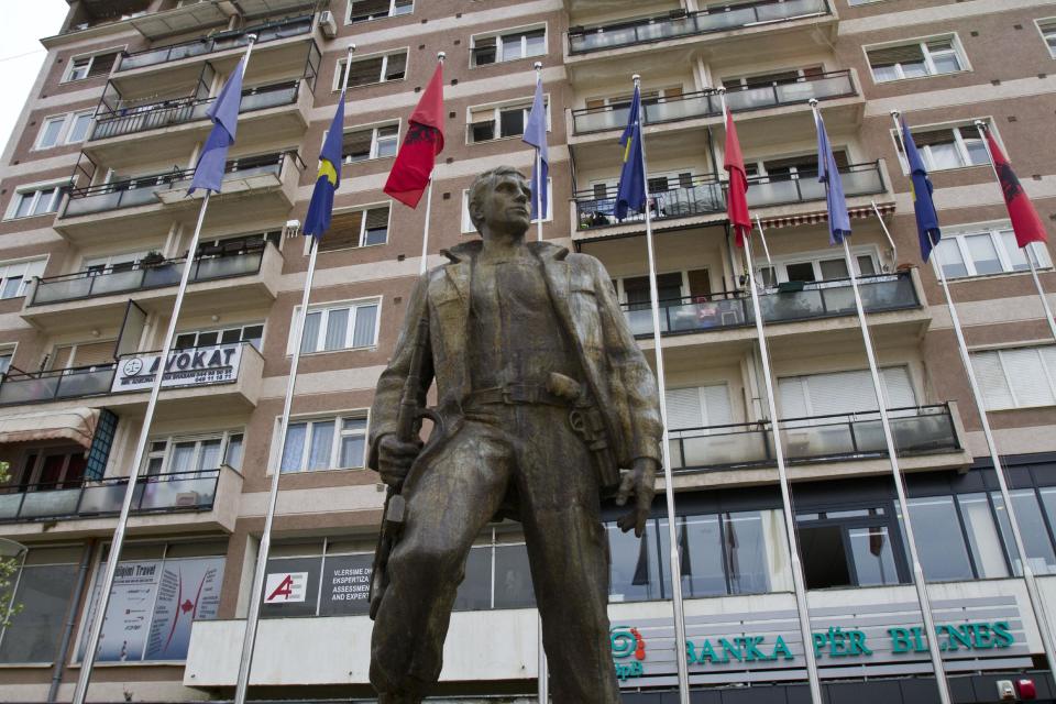 Kosovo and Albanian flags tower over a bronze statue, put up in memory of a Kosovo Liberation Army member in Kosovo capital Pristina on Friday, April 4, 2014. Former guerrillas have dismissed EU plans to set up an international tribunal to try former members of the Kosovo Liberation Army as anti Albanian. (AP Photo/Visar Kryeziu)