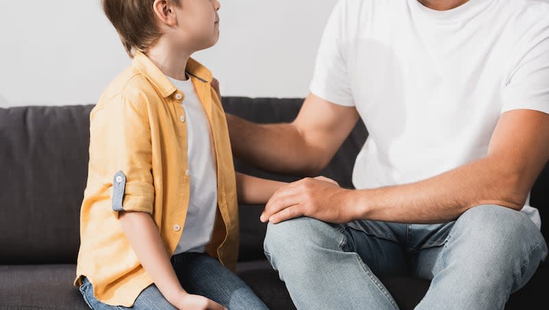 A parent talks to a child on a couch. A recent study from Preply examined the impact of parental language practices.