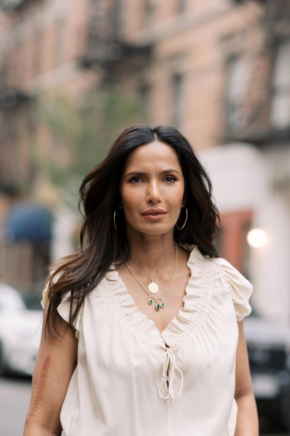 A woman in a city setting looks into the camera.