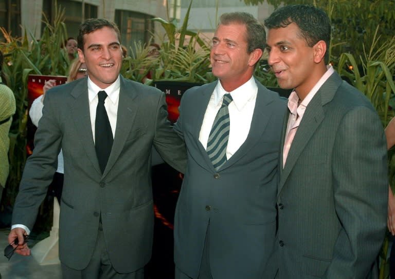 Joaquin Phoenix (L) and Mel Gibson (C) pose with director M. Night Shyamalan at the premiere of the movie "Signs" in New York in 2002