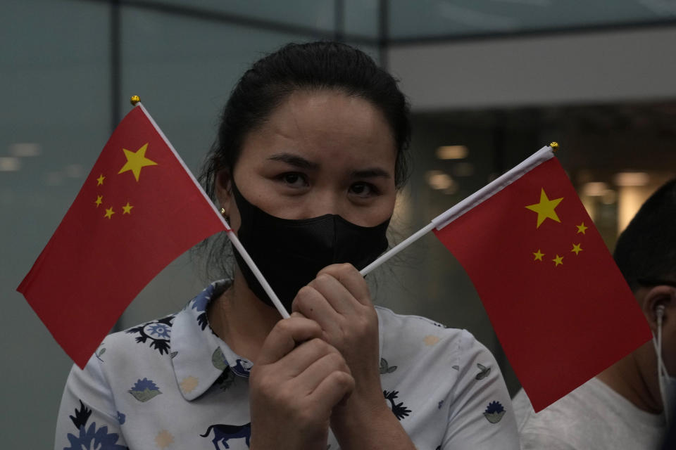 A supporter of Huawei CFO Meng Wanzhou holds up Chinese national flags at the Shenzhen Bao'an International Airport in Shenzhen in southern China's Guangdong Province, Saturday, Sept. 25, 2021. A top executive from global communications giant Huawei Technologies returned to China on Saturday following what amounted to a high-stakes prisoner swap with Canada and the U.S. (AP Photo/Ng Han Guan)