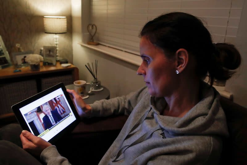 Teacher Wendy Couldridge watches on a device as Britain's Prime Minister Boris Johnson announces a lockdown in England