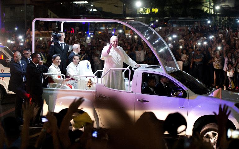 Pope Francis waves to Filipino Catholics as his motorcade passes by in Manila on January 15, 2015