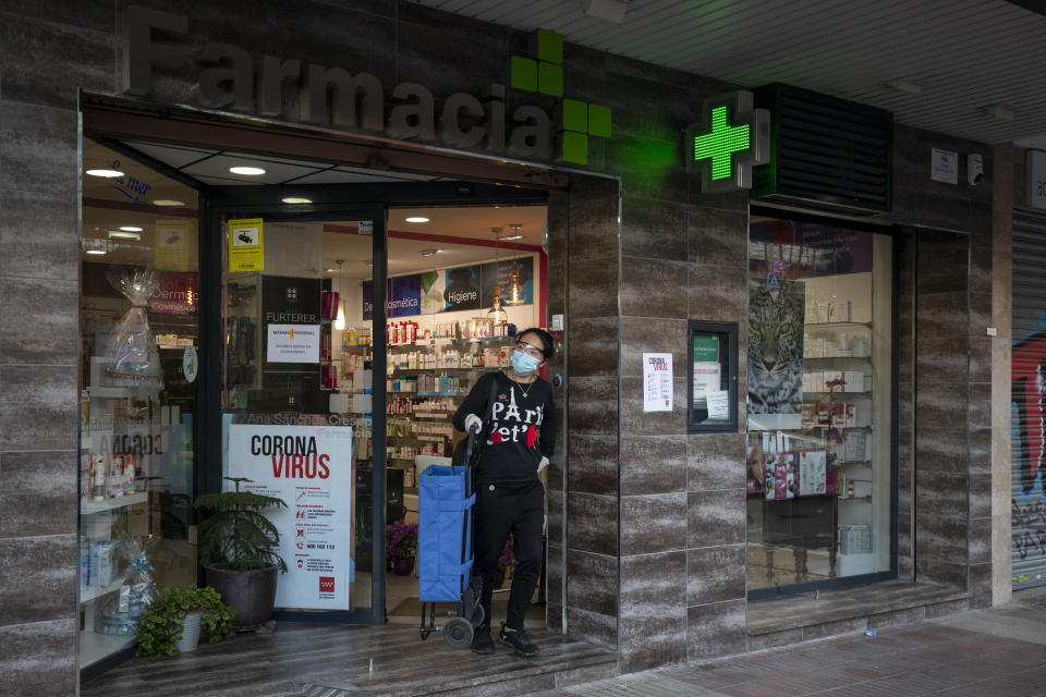 A woman wears a protective mask as she leaves a pharmacy 