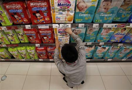 An Aeon Co Ltd's supermarket staff adjusts a slip of paper informing the two-package-per-family limit on Kao Corp's 'Merries' brand diapers on a display shelf at its Chiba outlet, east of Tokyo, March 31, 2014. REUTERS/Yuya Shino