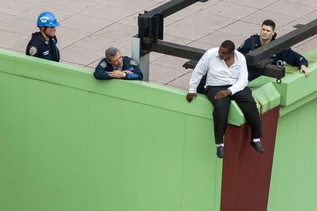 A man threatening suicide sits on a building ledge in New York's Times Square area, October 16, 2014. REUTERS/Brendan McDermid