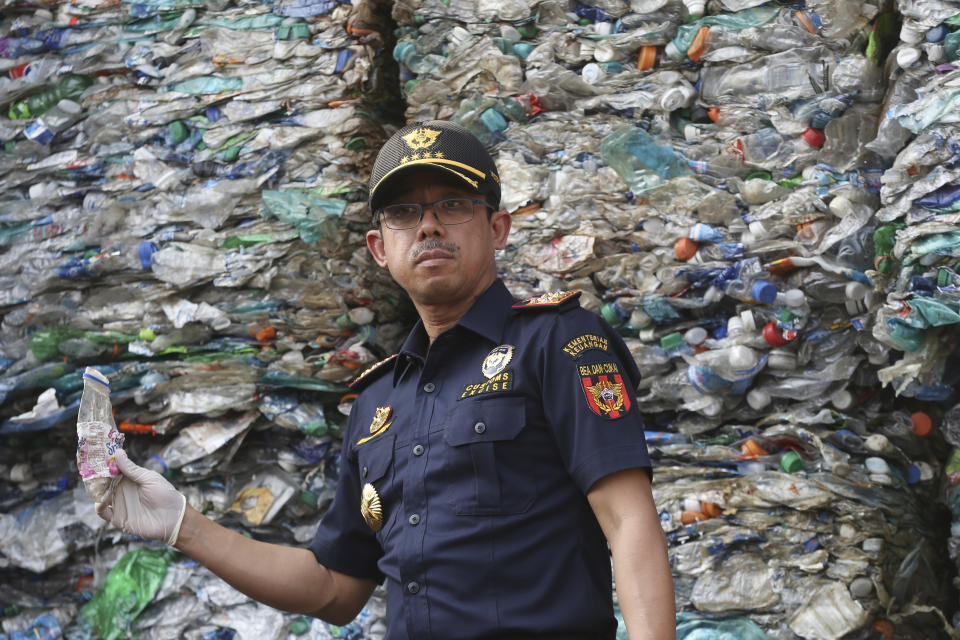 Director General of Indonesian Customs and Excise Heru Pambudi holds plastic bottle from containers full of plastic waste at Tanjung Priok port in Jakarta, Indonesia Wednesday, Sept. 18, 2019. Indonesia is sending hundreds of containers of waste back to Western nations after finding they were contaminated with used plastic and hazardous materials. (AP Photo/Achmad Ibrahim)