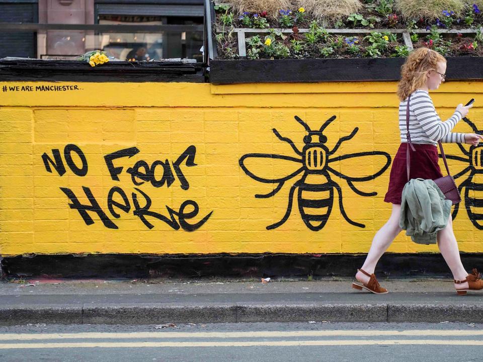 A woman passes a street-art graffiti mural, created following the May 22 terror attack at the Manchester Arena, featuring bees, which are synonymous with Manchester as a symbol of the city's industrial heritage, in Stevenson Square, Manchester (Getty Images)