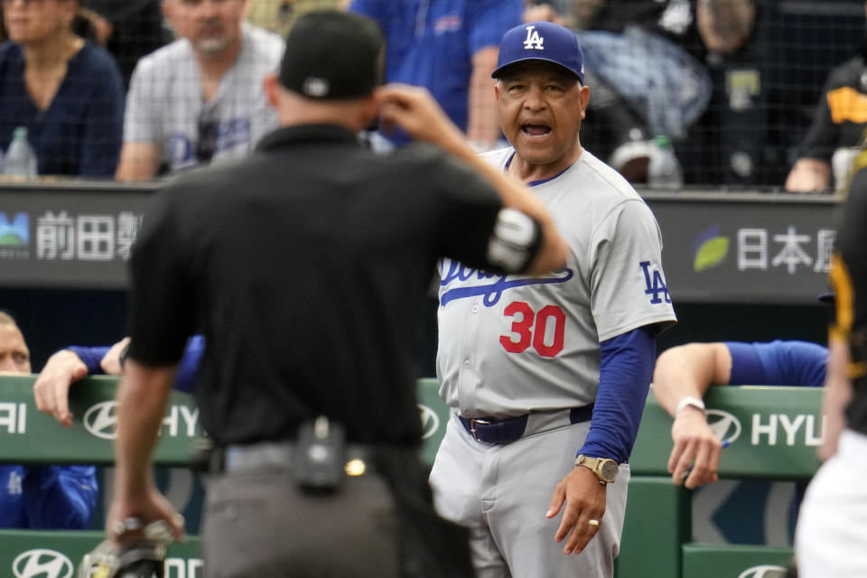 Los Angeles Dodgers manager Dave Roberts (30) requests from umpire Dan Merzel a replay review of a line drive hit by Shohei Ohtani during the first inning of the team's baseball game against the Pittsburgh Pirates in Pittsburgh, Thursday, June 6, 2024. Ohtani was originally called out, but had a single after review. (AP Photo/Gene J. Puskar)