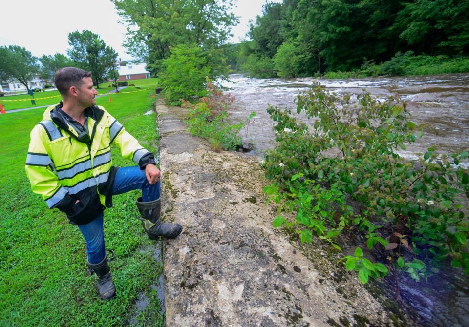 Hinsdale, N.H., firefighter Bill Hodgman looks at the water levels on the Ashuelot River as fire personnel block off part of the Millstream Riverfront Park in Hinsdale, N.H., as the water rises, Monday, July 10, 2023. (Kristopher Radder/The Brattleboro Reformer via AP)