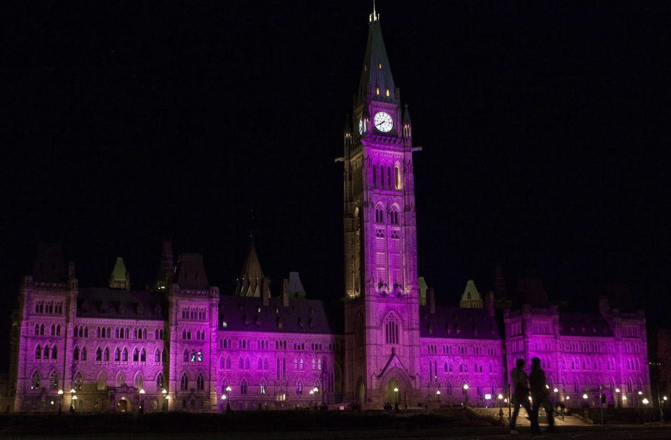 People walk past as the Parliament Buildings are lit up in pink in support of Breast Cancer awareness month in Ottawa on Thursday, Oct. 7, 2010. THE CANADIAN PRESS/Pawel Dwulit