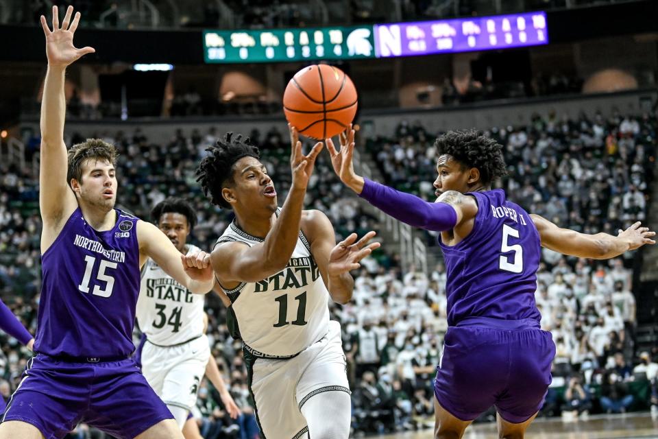 Michigan State's A.J. Hoggard, center, passes the ball between Northwestern's Ryan Young, left, and Julian Roper II during the first half on Saturday, Jan. 15, 2022, at the Breslin Center in East Lansing.