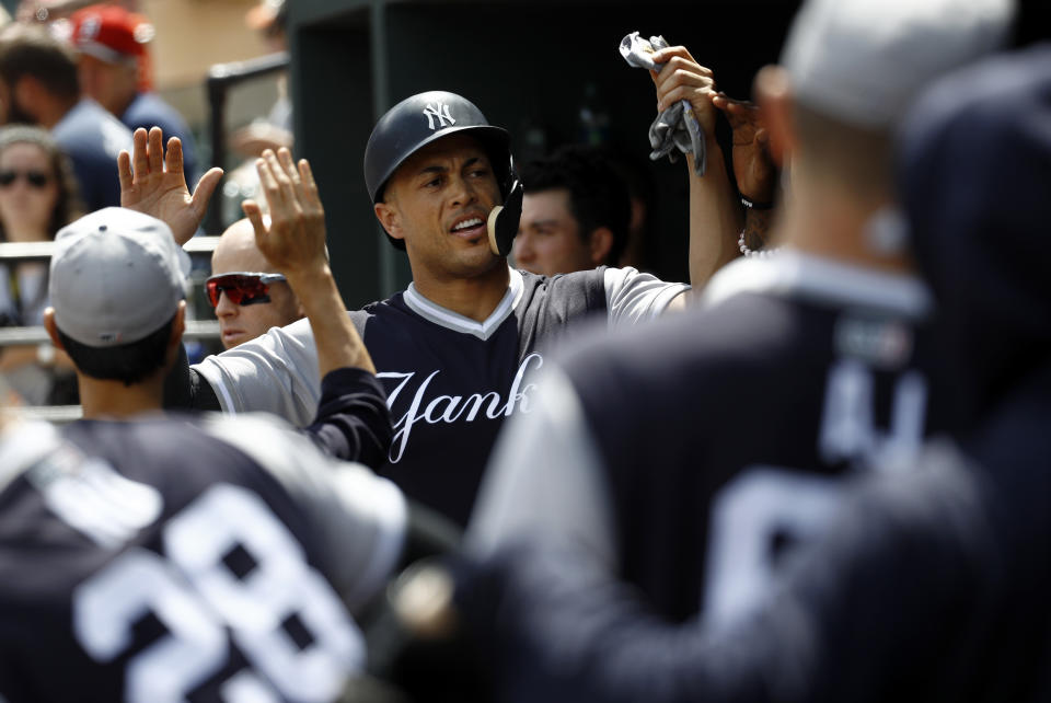 New York Yankees' Giancarlo Stanton high-fives teammates in the dugout after scoring on Miguel Andujar's fielder's choice groundout in the first inning of a baseball game against the Baltimore Orioles, Saturday, Aug. 25, 2018, in Baltimore. (AP Photo/Patrick Semansky)