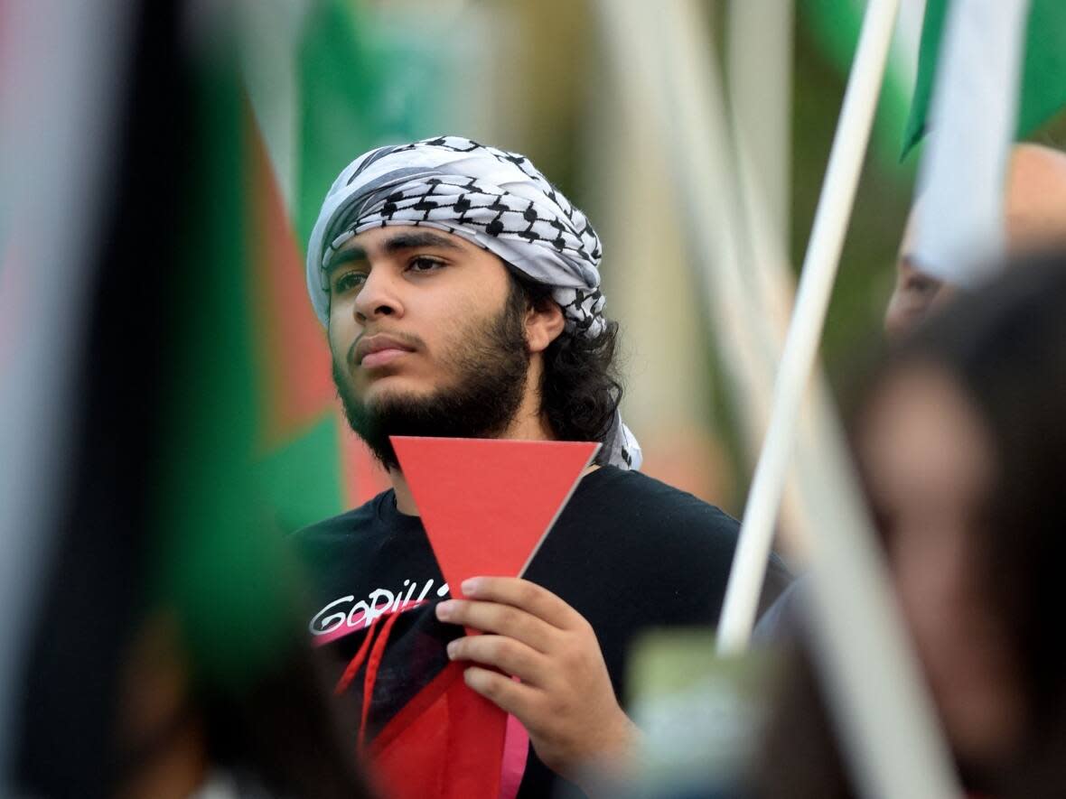 A Palestinian protester holds a placard bearing the inverted red triangle during a rally supporting the Gaza Strip on Dec. 11, 2023, in the occupied West Bank city of Hebron.  (Hazem Bader/AFP/Getty Images - image credit)