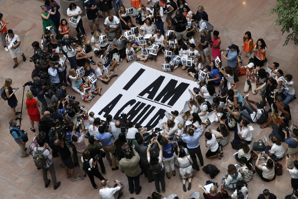 Families with young children gather around a sign on the ground that reads 