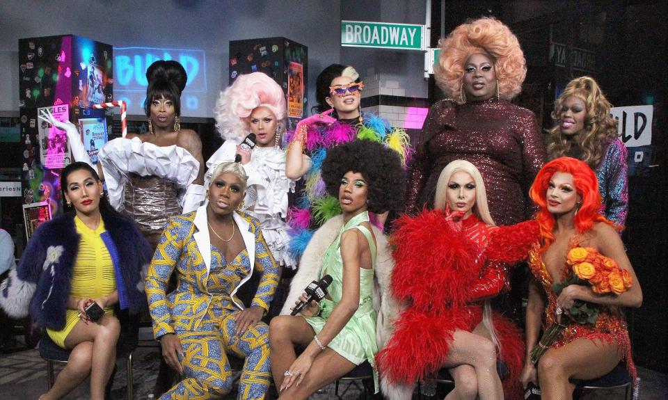 Rupaul's drag race contestants sitting on chairs dressed in drag