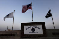 U.S. NAVAL BASE GUANTANAMO, CUBA - MAY 31: (EDITORS NOTE: IMAGE REVIEWED BY U.S. MILITARY PRIOR TO TRANSMISSION) Flags wave above the sign posted at the entrance to Camp Justice, the site of the U.S. war crimes tribunal compound on May 31, 2009 at U.S. Naval Base Guantanamo Bay, Cuba. Former child soldier Omar Khadr, the Canadian citizen captured on the battlefield in Afghanistan in 2002 is expected to appear in a military commission hearing tomorrow with the charge of providing support to terrorism after allegedly throwing a grenade that killed a US soldier. This trial marks the first hearing of the Bush-era war crimes tribunals to take place under U.S. President Barack Obama. (Photo by Brennan Linsley-Pool/Getty Images)