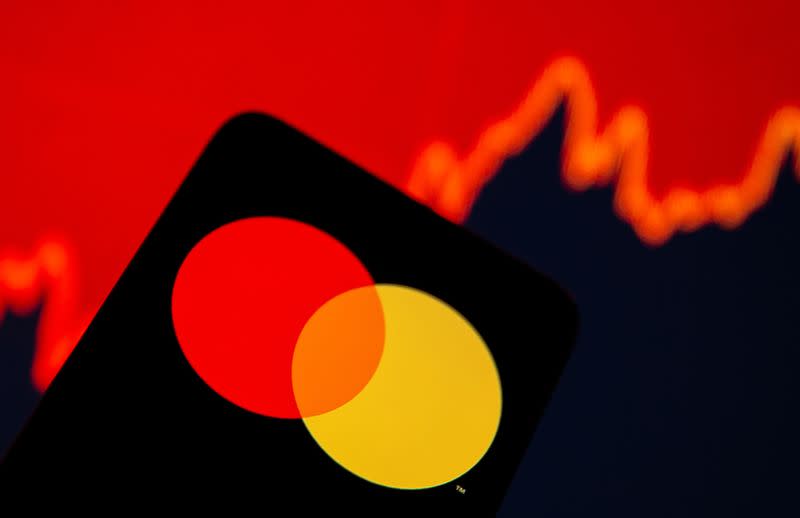 Smartphone with Mastercard logo is seen in front of displayed stock graph in this illustration