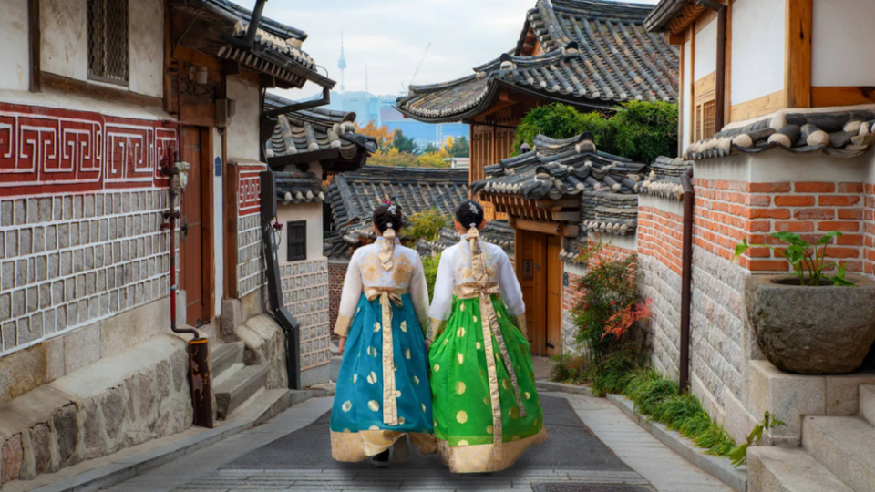 Dos mujeres caminan por una calle vistiendo trajes tradicionales en Corea del Sur.
