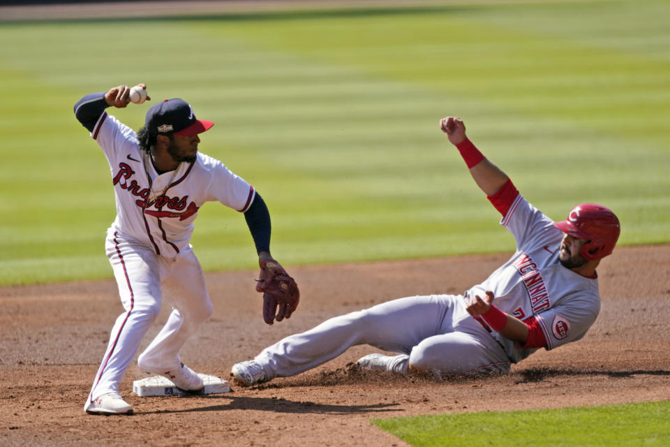 Atlanta Braves second baseman Ozzie Albies (1) throws to first after forcing out Cincinnati Reds' Eugenio Suarez (7) during the second inning in Game 2 of a National League wild-card baseball series, Thursday, Oct. 1, 2020, in Atlanta. The Reds' Mike Moustakas was safe at first. (AP Photo/John Bazemore)