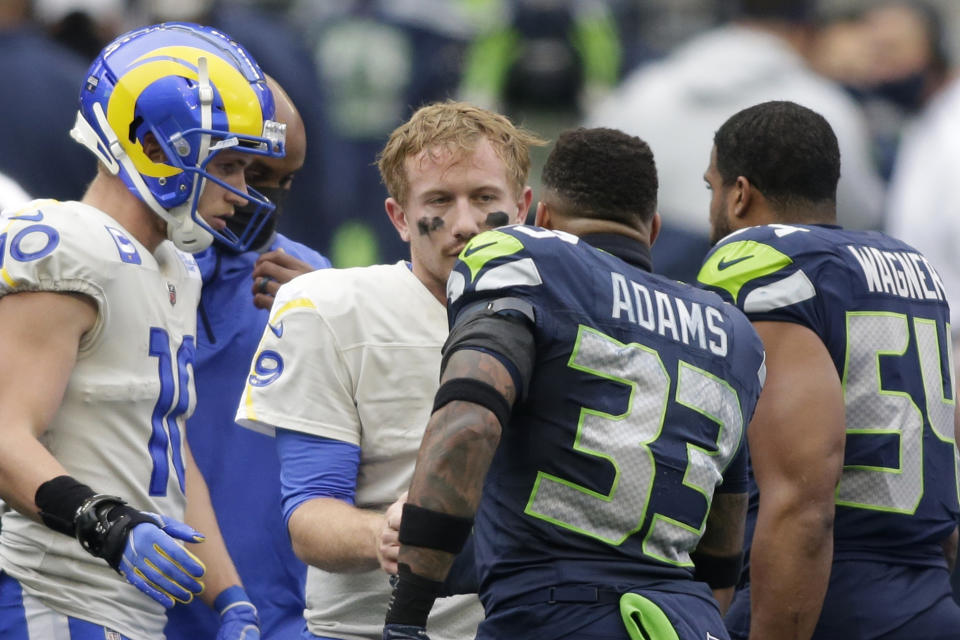 Seattle Seahawks strong safety Jamal Adams (33) talks with Los Angeles Rams quarterback John Wolford after Wolford was injured and was leaving during the first half of an NFL wild-card playoff football game, Saturday, Jan. 9, 2021, in Seattle. (AP Photo/Scott Eklund)