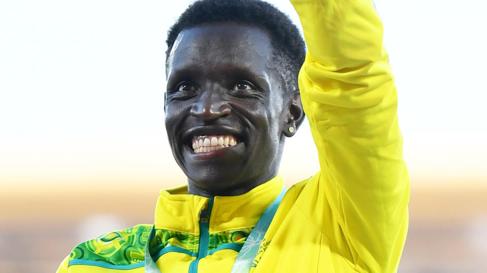 Peter Bol raises his arm in celebration on the podium at the Commonwealth Games.