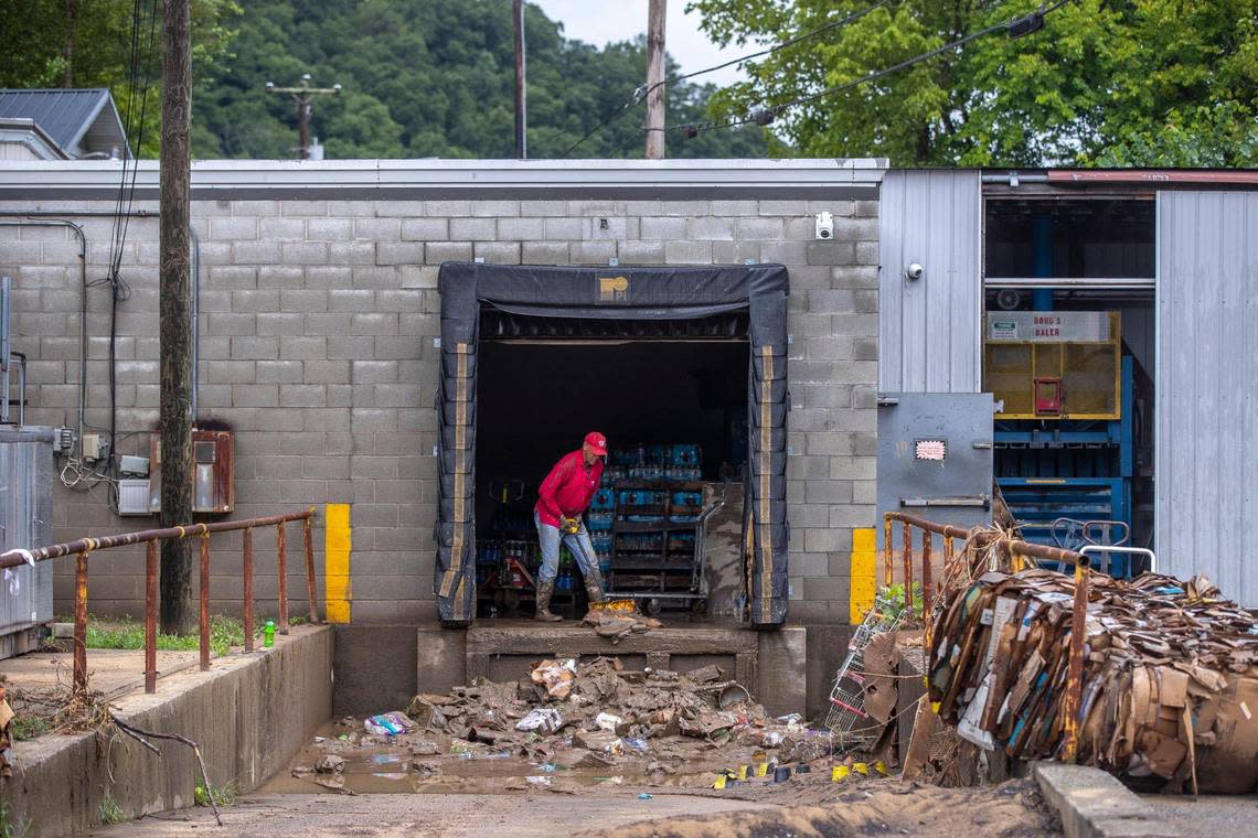 Arthur Christian, co-owner of Isom IGA in Isom, Ky., with his wife Gwen, uses a snow shovel to clear mud from the backroom of the grocery store on Monday, Aug. 1, 2022.
